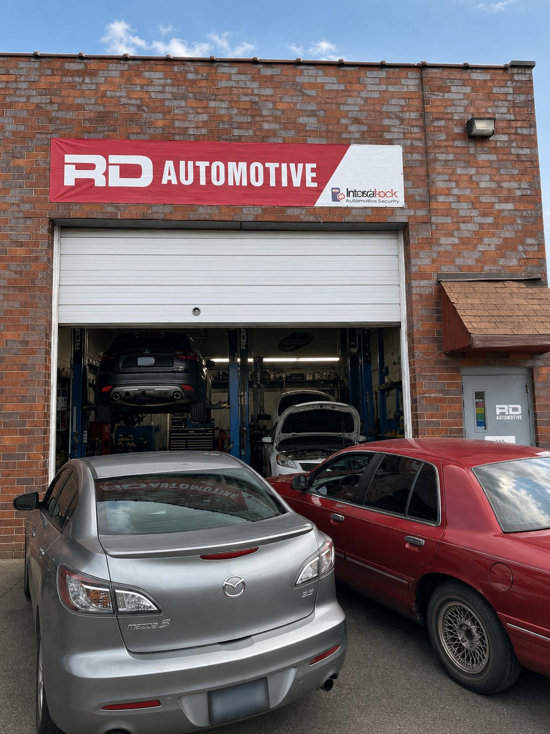 The front of RD Automotive on Industrial Lane, with the red RD Automotive banner above the open bay door